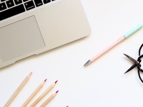 A clean minimalist desk setup featuring a laptop and colorful stationery in a home office.