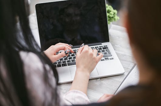 Close-up of a woman's hands typing on a laptop at a desk, perfect for business and technology concepts.