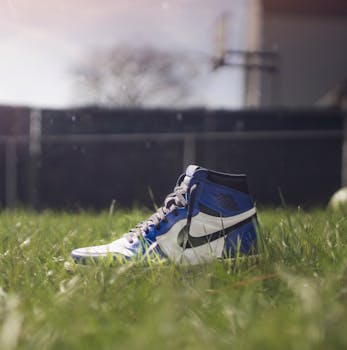 Close-up of a blue sneaker on lush grass in bright sunlight.