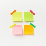 Four colorful sticky notes on white backdrop with vibrant tape. Perfect for office or organizational themes.