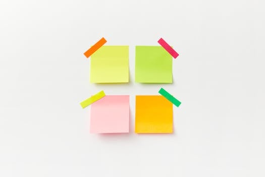 Four colorful sticky notes on white backdrop with vibrant tape. Perfect for office or organizational themes.